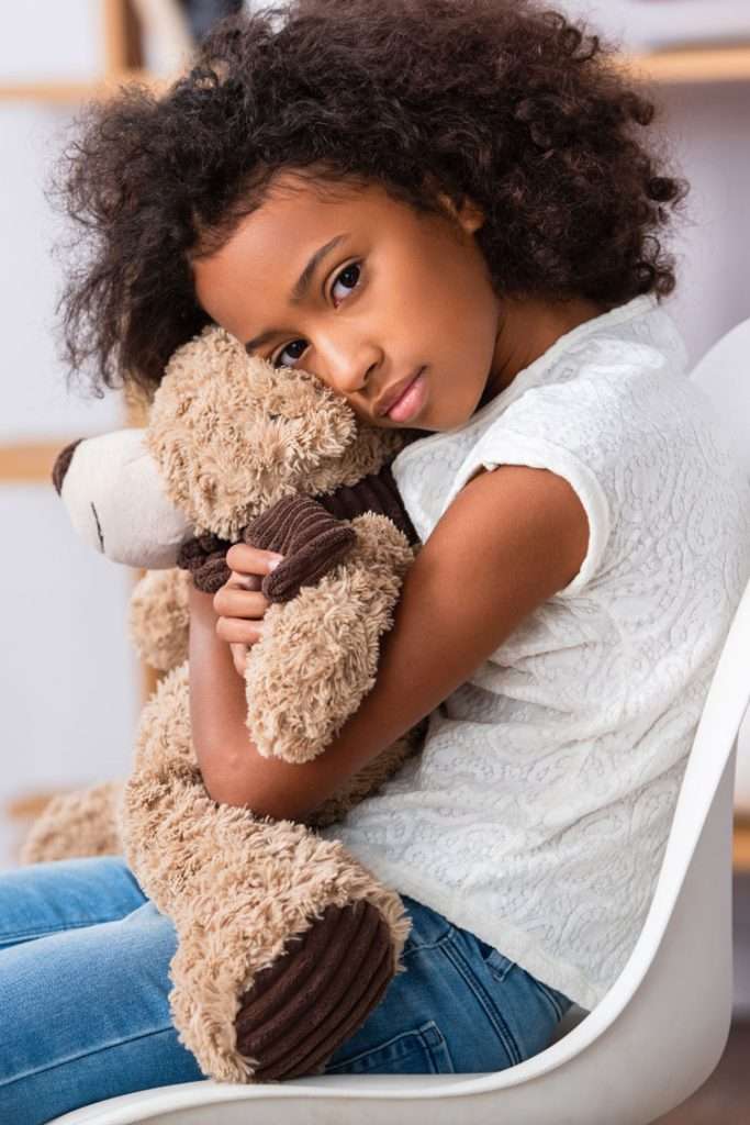 Girl with a teddy bear showing emotions related to speech autism.