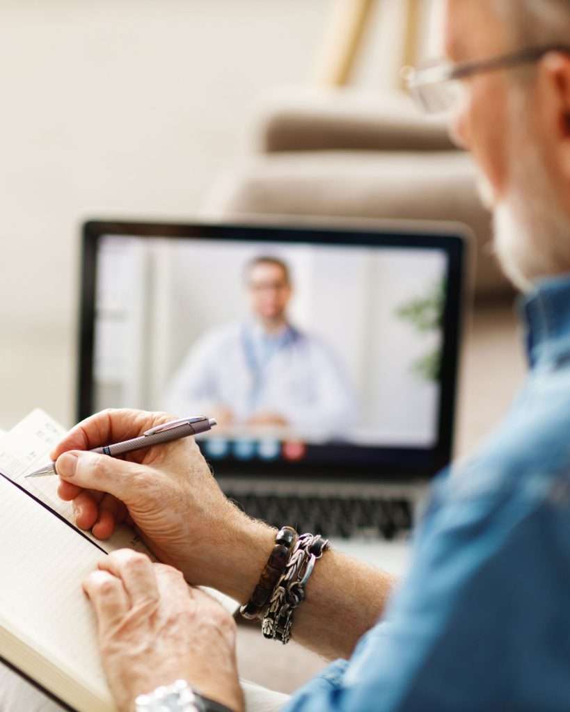 A senior man on his laptop, on an online speech therapy session for adults at home.