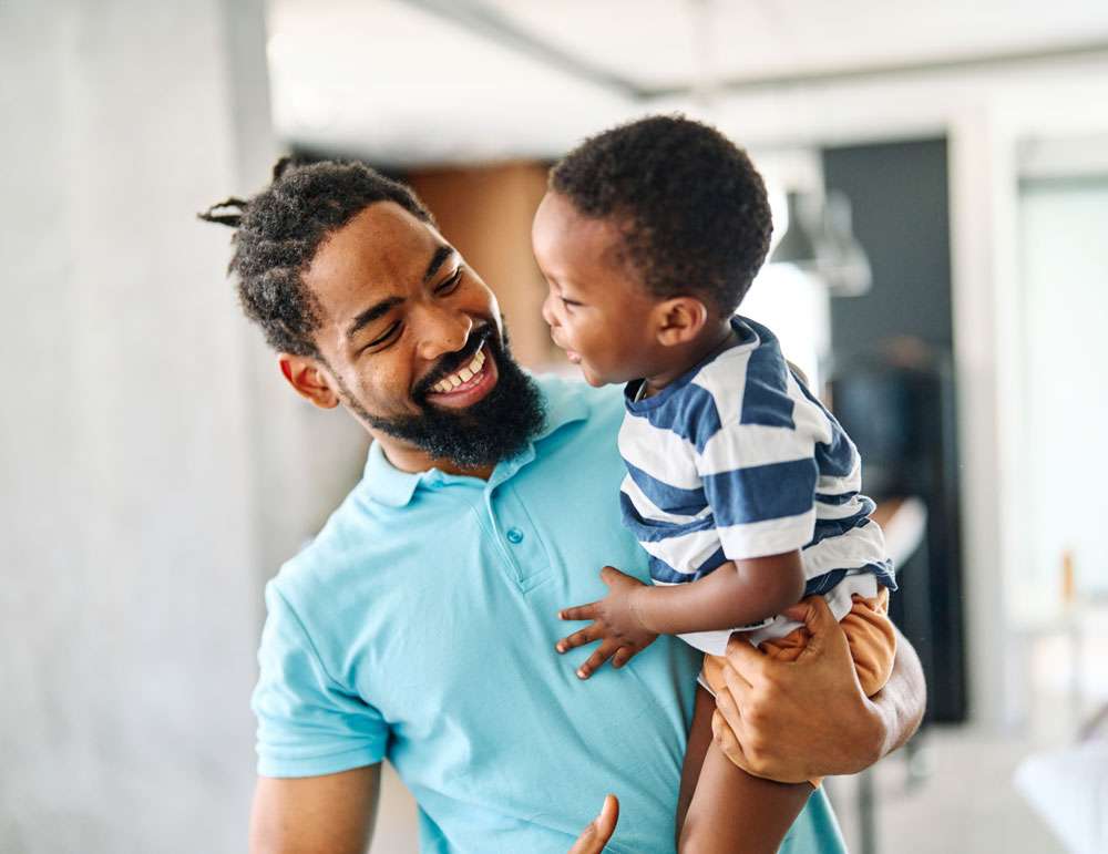 Father holding son, smiling after speech improvement with Virtual Speech Therapy.