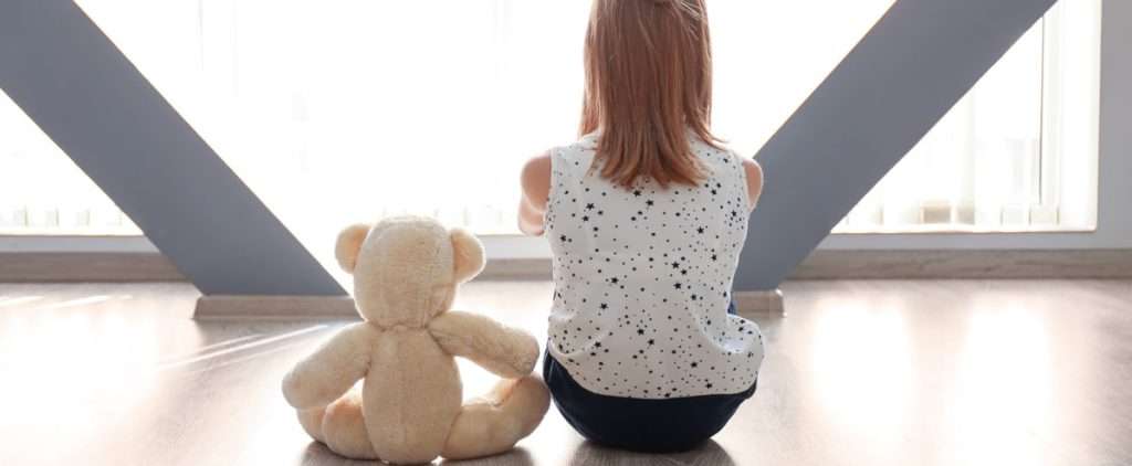 Girl facing window with teddy, symbolizing signs a child may need to see a pediatric speech pathologist.