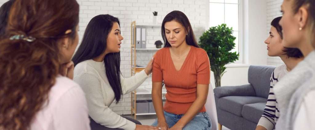 Women in a circle with one sad, showing support for autism camouflaging behaviors among women.