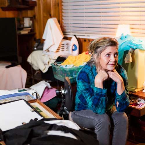 Woman sitting in cluttered room, symbolizing executive function challenges in women with autism.