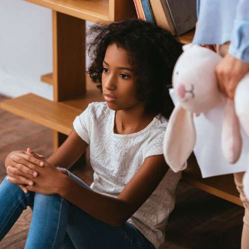 Girl on the floor with a child’s hand holding a bunny, highlighting autism symptoms in girls.