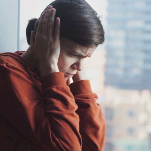 Woman covering ears, looking sad, depicting emotional regulation problems, a symptom of autism in women.
