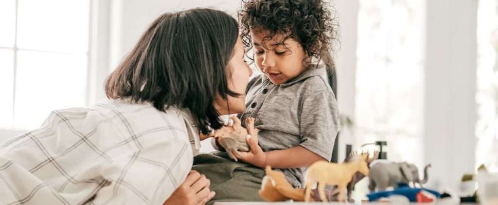 A toddler boy with his mom playing with animal toys.